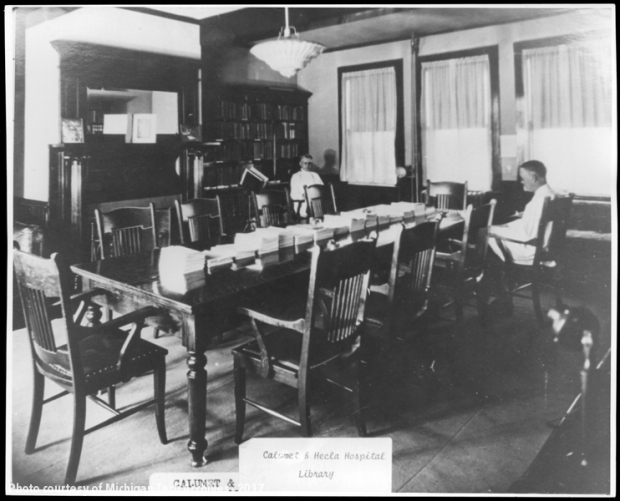 Two men seated near long table in library