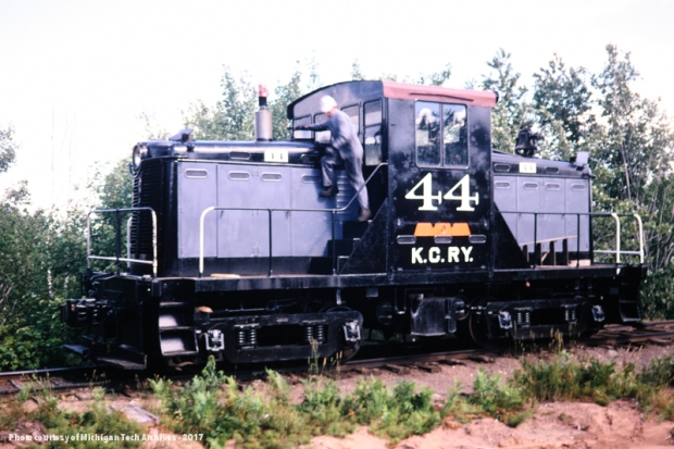 Diesel locomotive on tracks with man looking underneath the hood